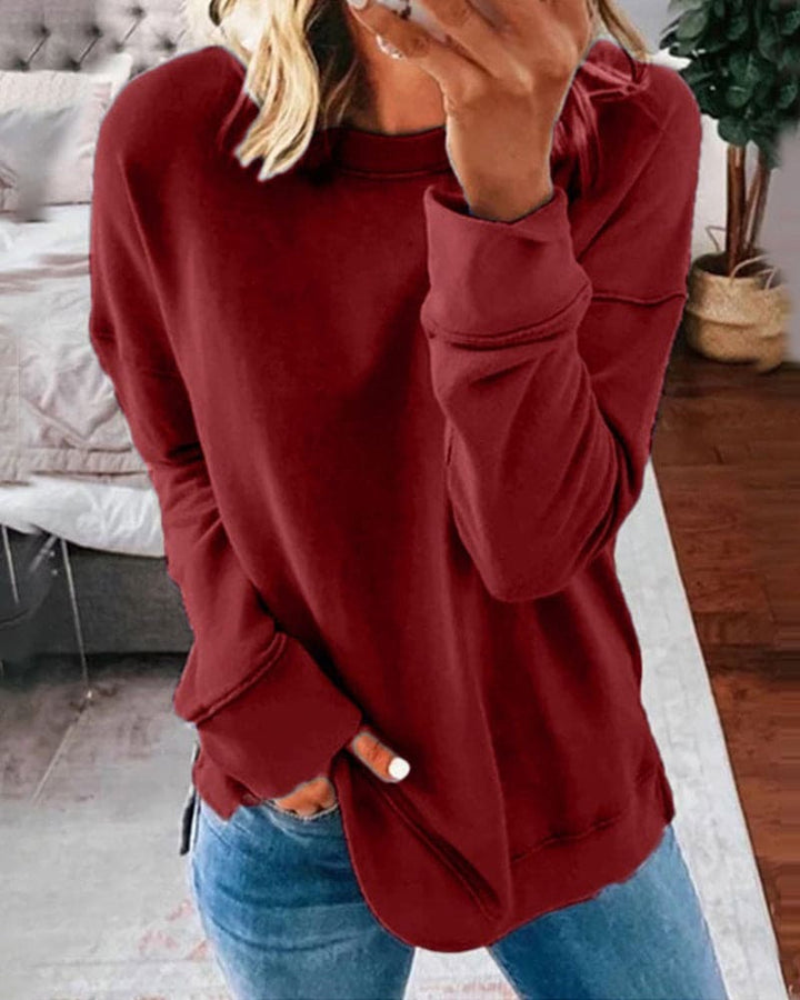 Front view of a model wearing a maroon oversized crew-neck sweatshirt with a rounded hem and side split