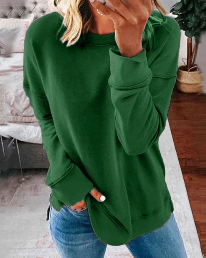 Close up view of a model wearing a green oversized crew-neck sweatshirt with her hand in her jeans pocket