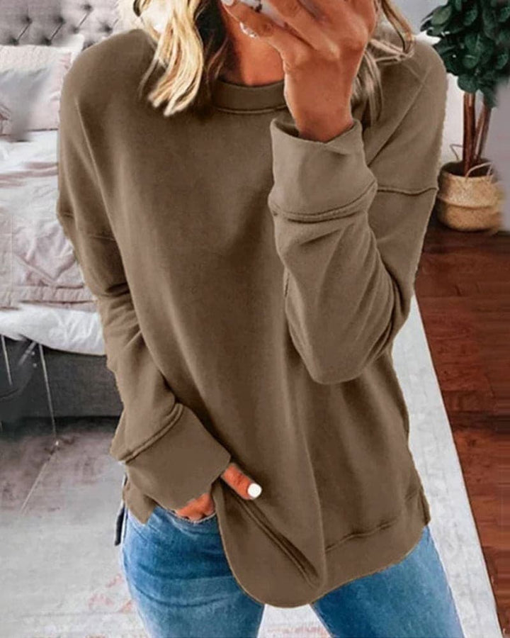 Front view of a model wearing a brown oversized crew-neck sweatshirt with a rounded hem and side split