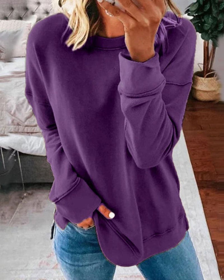 Close up view of a model wearing a purple oversized crew-neck sweatshirt with her hand in her jeans pocket