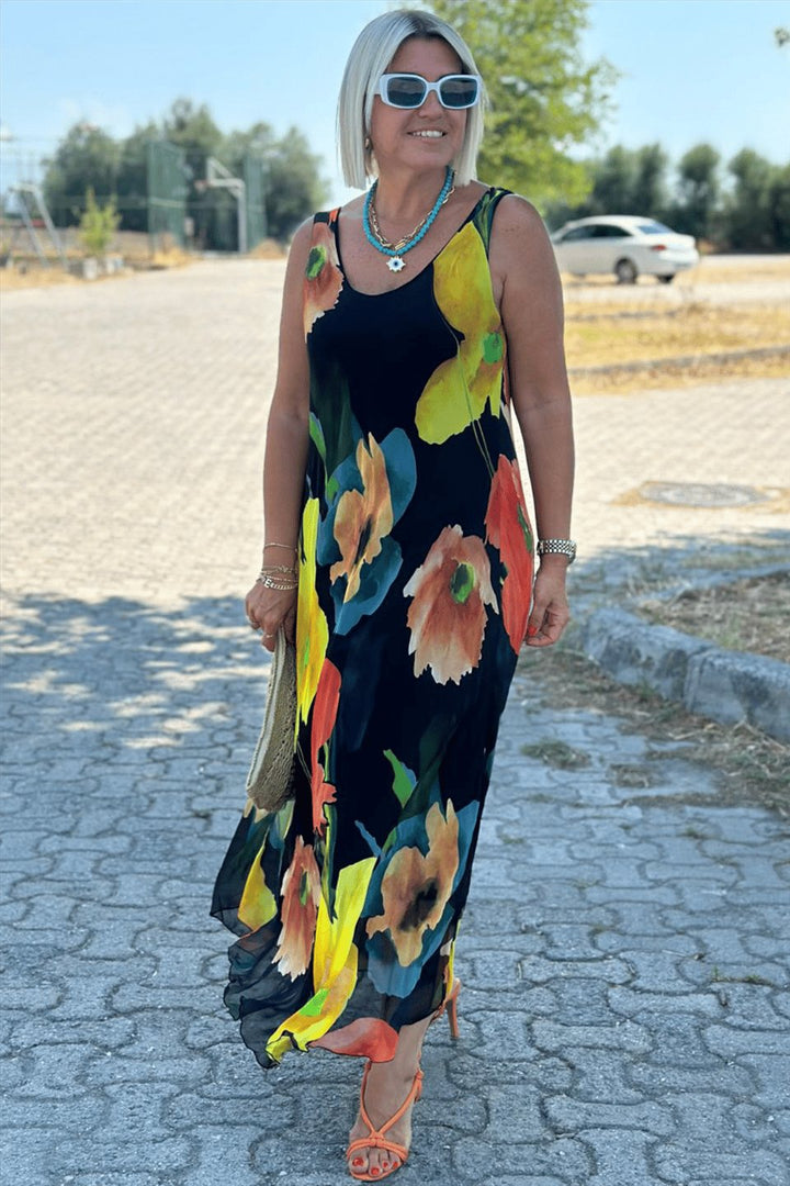 Front view of model wearing a black floral silk chiffon maxi dress with a U-neckline and orange heels