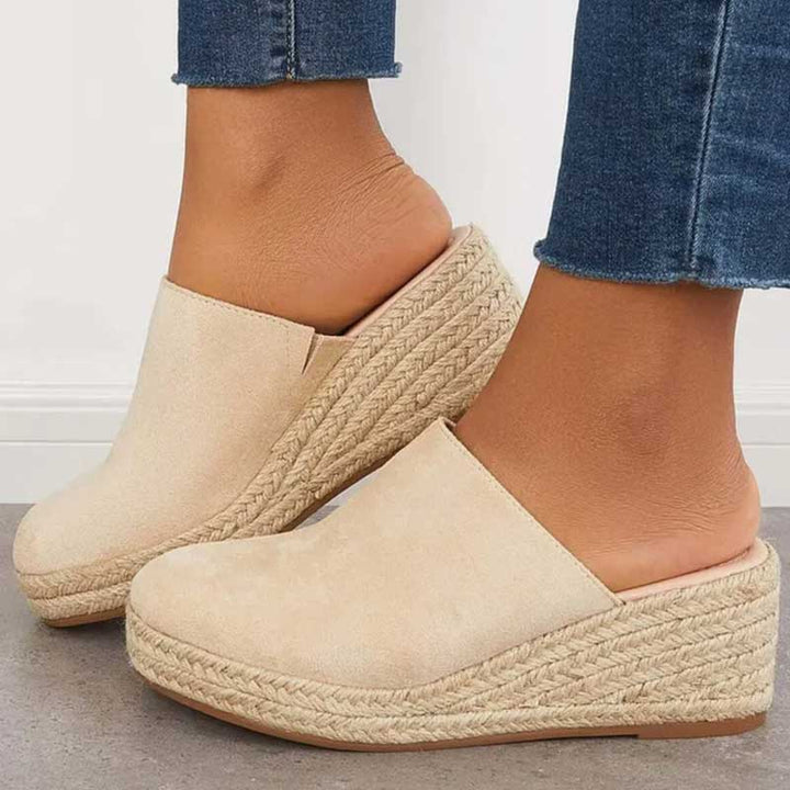 Side view, a model wearing beige Wendy Platform Sandals with espadrille wedge soles and frayed denim jeans