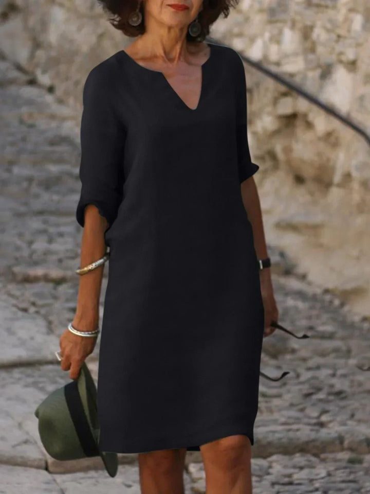 Front view of a woman wearing a black vintage solid mini dress with a V-neck and three-quarter sleeves