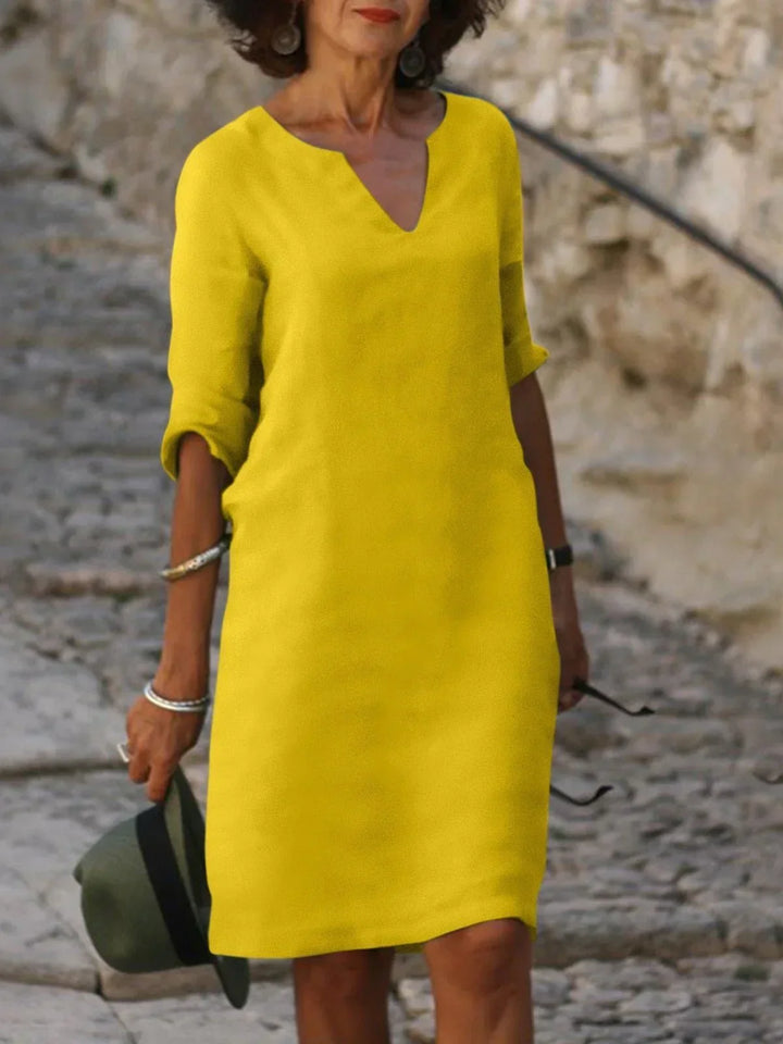 Front view of a woman wearing a yellow vintage solid mini dress with a V-neck and three-quarter sleeves