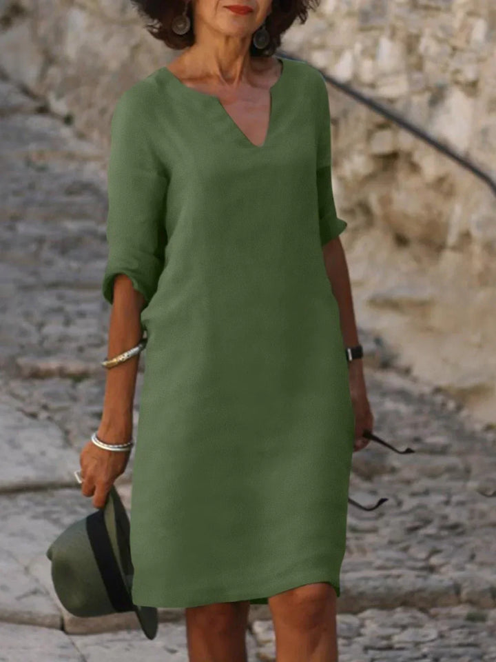 Front view of a woman wearing a green vintage solid mini dress with a V-neck and three-quarter sleeves