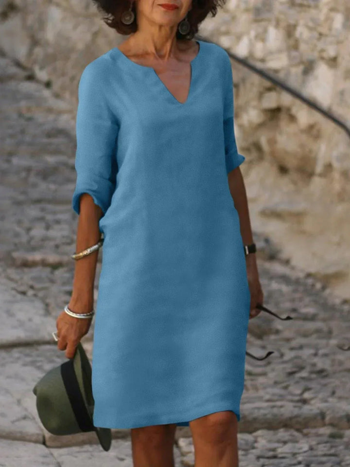 Front view of a woman wearing a blue vintage solid mini dress with a V-neck and three-quarter sleeves