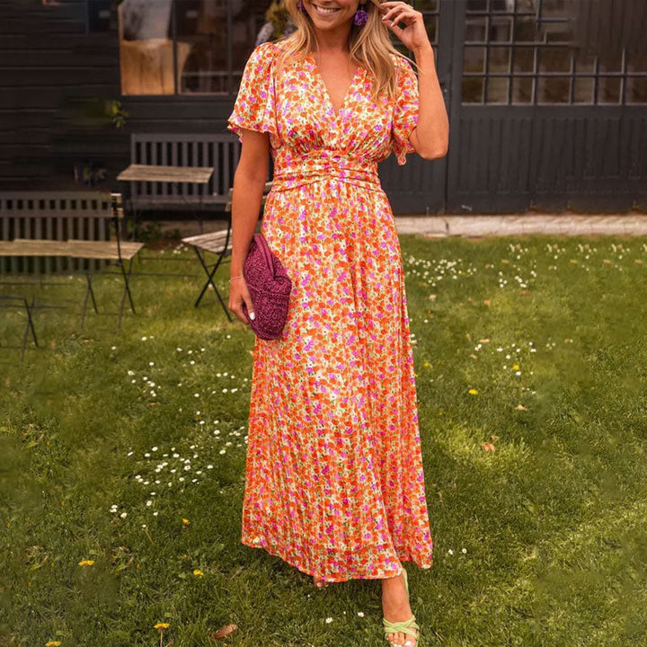 Front view, model in a floral print breezy summer dress with V-neck, short sleeves, ruched waist, and pleated skirt
