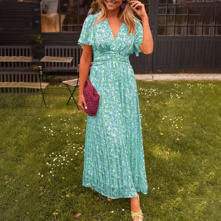 Front view, model in a floral print breezy summer dress with V-neck, short sleeves and a pleated maxi skirt, alternate angle
