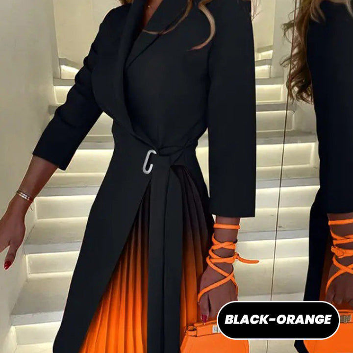 Close up of a model wearing a black pleated blazer dress with an orange pleated skirt and silver buckle, alternate angle