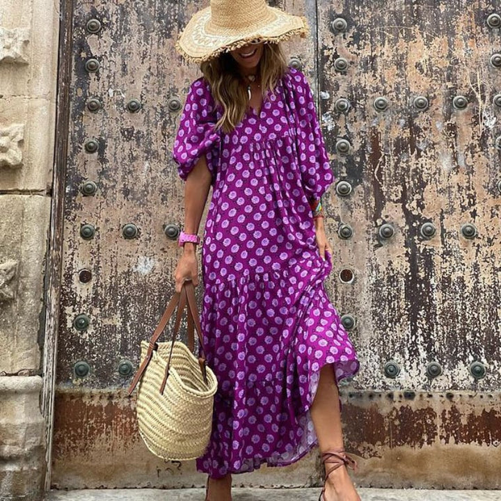 Front view of a woman in a purple geometric print boho puff sleeve maxi dress and a straw hat
