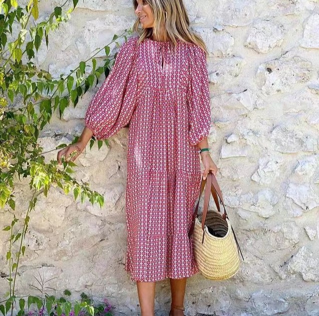 Side view of a woman in a red and white geometric print boho puff sleeve maxi dress holding a straw bag