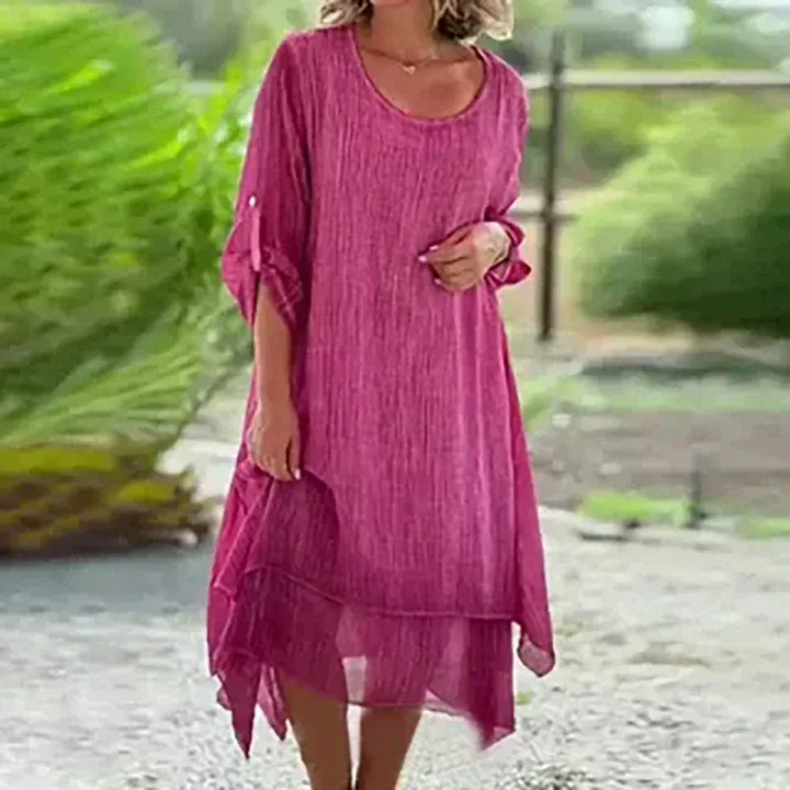 Close up, model wearing the magenta double-layer elegant dress with a textured fabric and rolled up sleeves