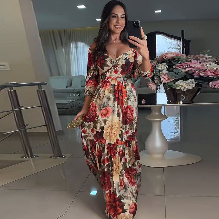 Front view of a woman wearing a boho floral maxi dress, holding a phone and a clutch in a living room