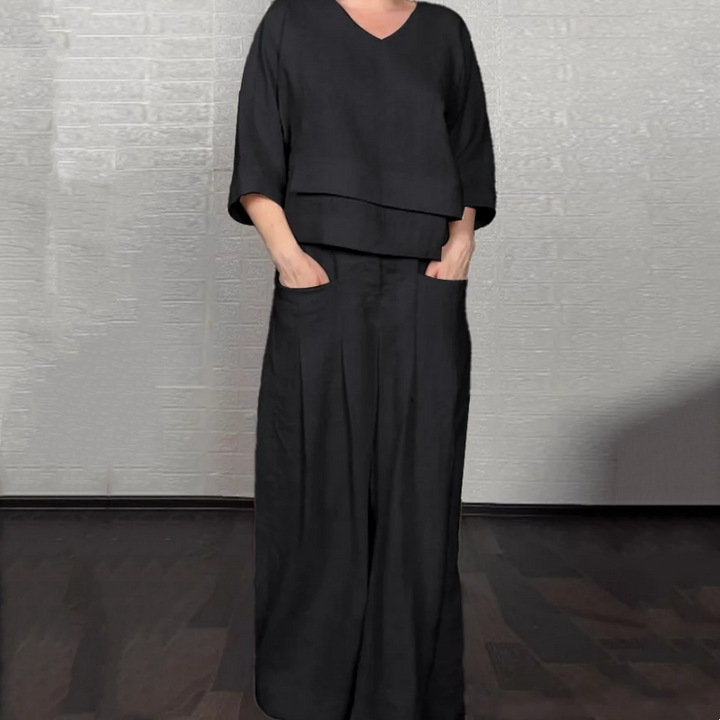 Front view worn by model, black V-neck jumpsuit with wide-leg pants and hands in pockets