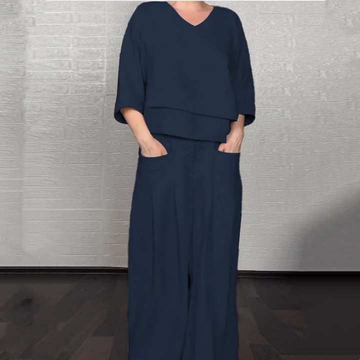 Front view worn by model, navy V-neck jumpsuit with wide-leg pants and hands in pockets