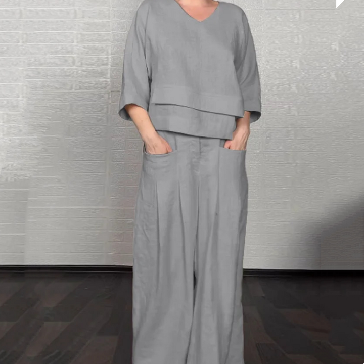 Front view worn by model, grey V-neck jumpsuit with wide-leg pants and hands in pockets