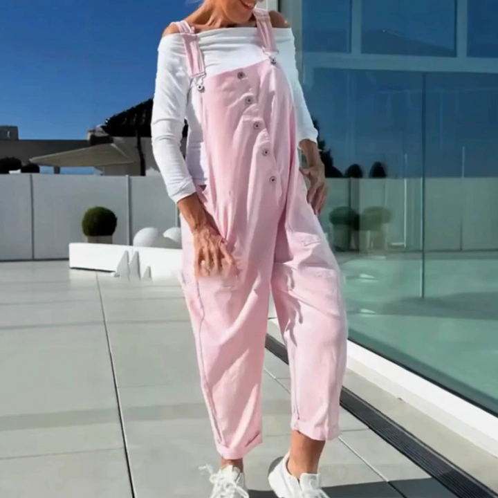 Three quarter view of a model wearing soft pantyhose with straps under pink overalls and a white top