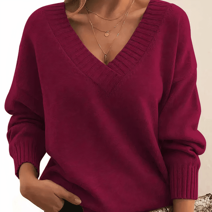 Burgundy V neck knit jumper with a hand in the pocket, front view