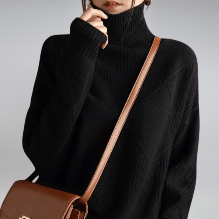 Close up of a model wearing a black check turtleneck knit sweater with textured diamond patterns and a brown bag