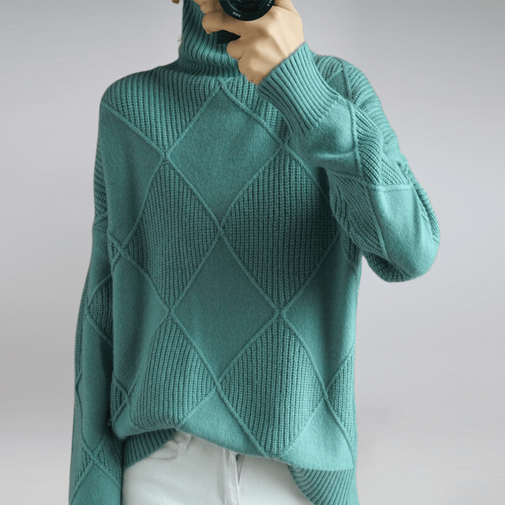 Front view of a model wearing a teal check turtleneck knit sweater with textured diamond patterns