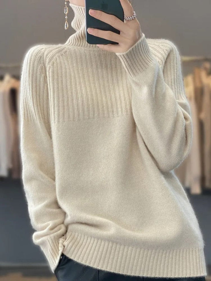 Front view of a model wearing a soft ribbed turtleneck jumper in cream with a phone and earrings