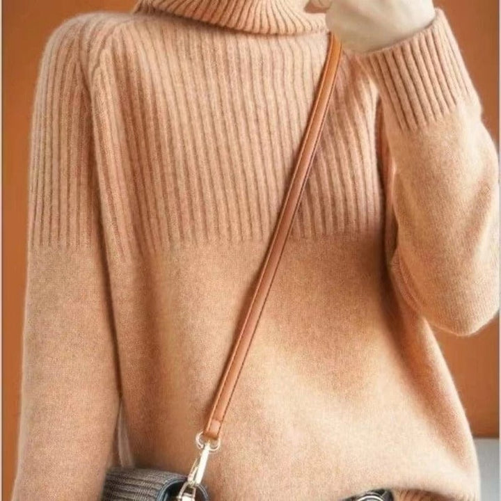 Close up view of a model wearing a soft brown ribbed turtleneck jumper with a shoulder bag