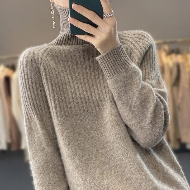Close up view of a model wearing a soft beige ribbed turtleneck jumper with a phone and ring