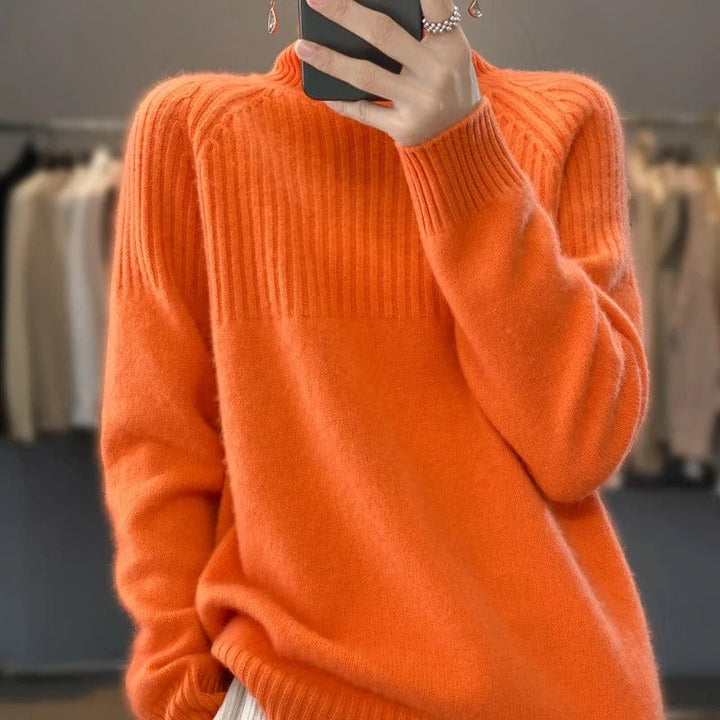 Close up view of a model wearing a bright orange ribbed turtleneck jumper with a phone and ring