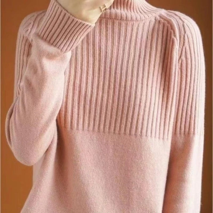 Close up view of a model wearing a soft pink ribbed turtleneck jumper with a gold ring