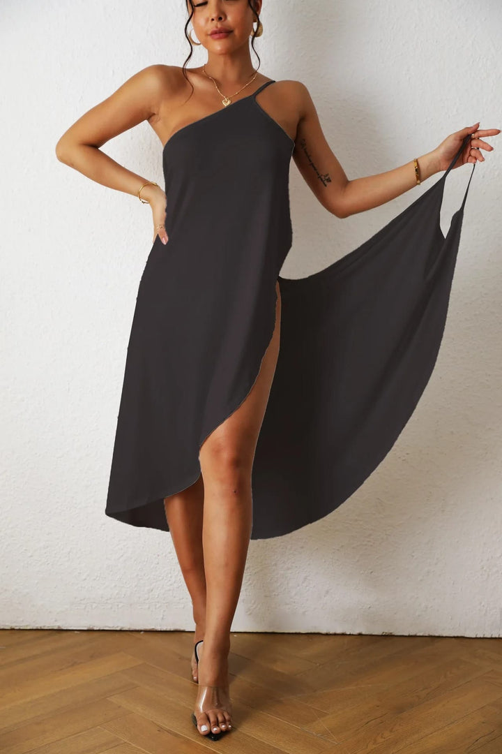 Front view of a model wearing a black multi-wear strappy beach dress with a high side split and one shoulder strap