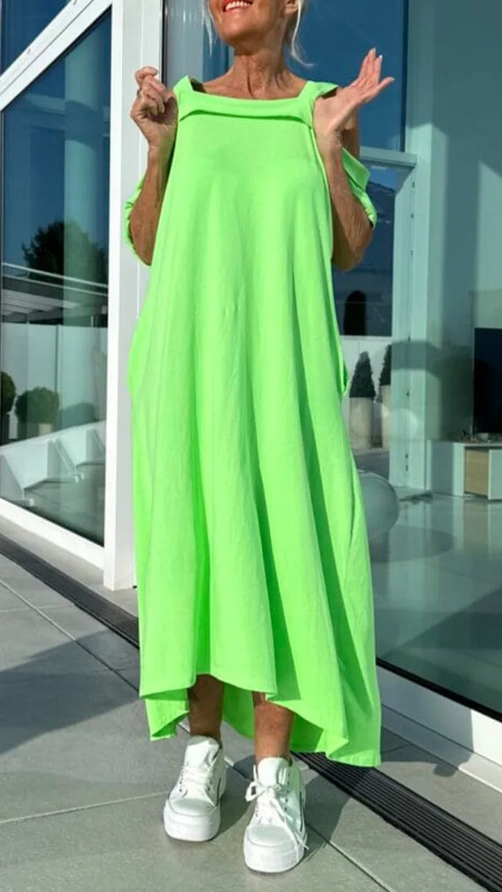 Front view, model wearing a bright green Brianna maxi dress with open shoulders and white platform sneakers