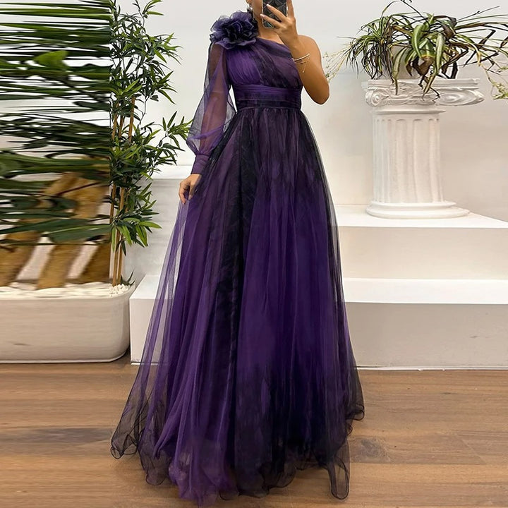 Front view of a model wearing a purple single sleeve tulle evening dress with a floral shoulder detail and full skirt