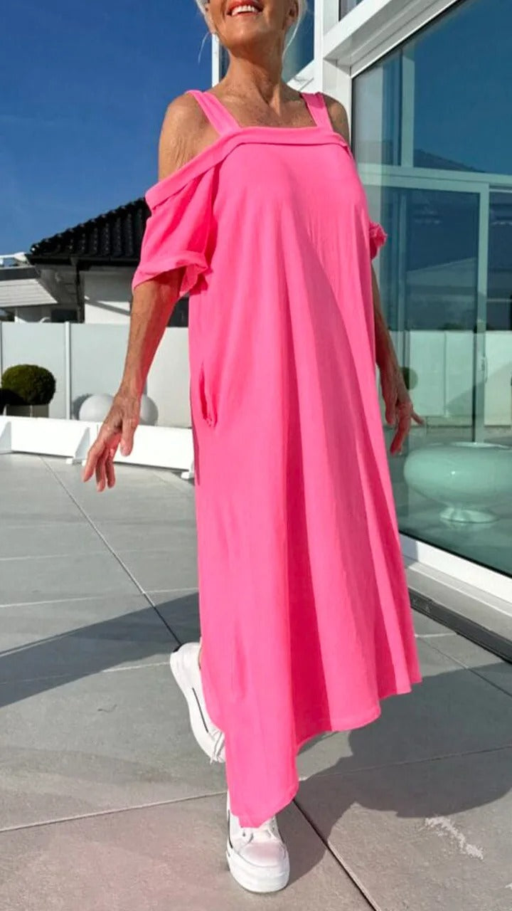 Three quarter view, model wearing a pink Brianna maxi dress with open shoulders and white platform sneakers