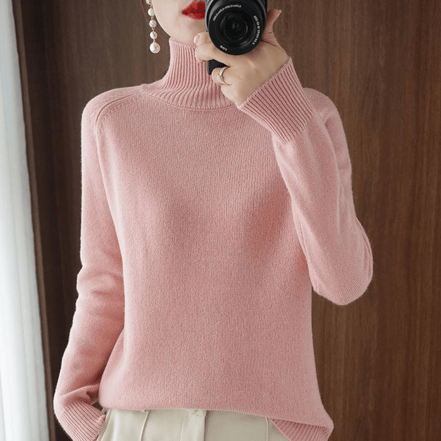 Worn by model, the pink turtleneck jumper with pearl earrings and a camera