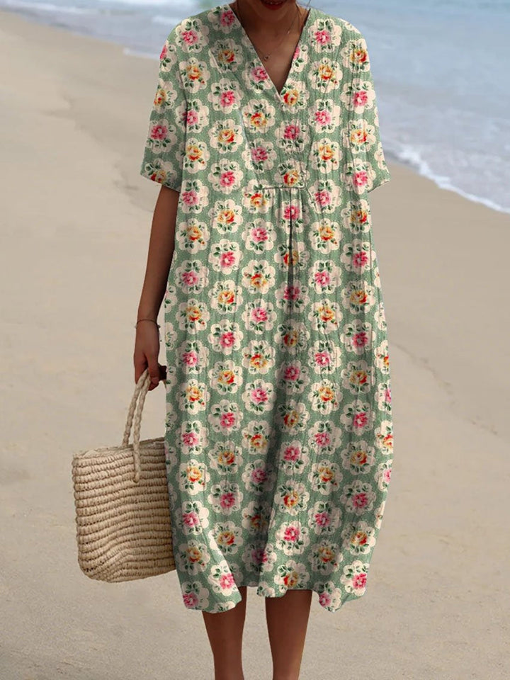 Front view, model wearing a green boho floral vintage dress with a straw bag on a beach
