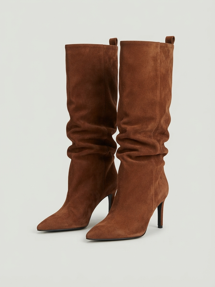 Brown suede knee high boots with a pointed toe, the pair seen from the front