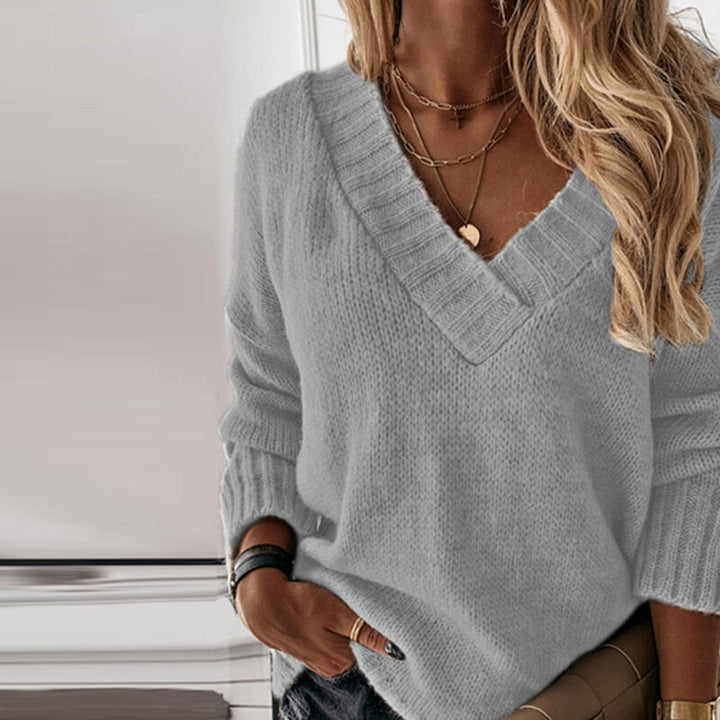 Close up of a model wearing the grey oversized V-neck wool knit jumper with layered necklaces and a watch