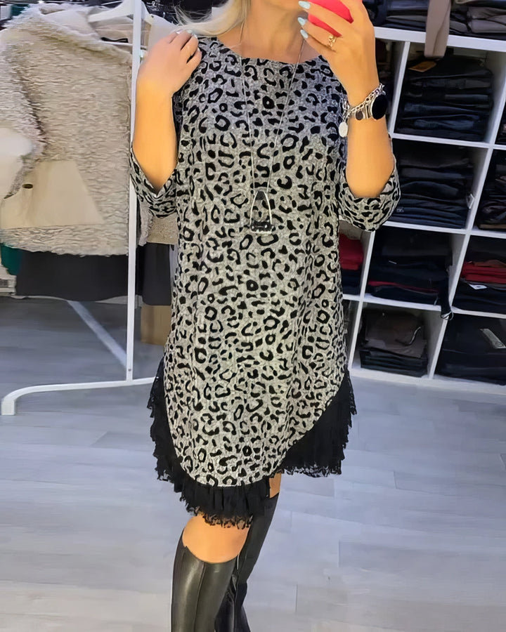 Front view of a model wearing a grey leopard print dress with black lace trim and knee-high boots