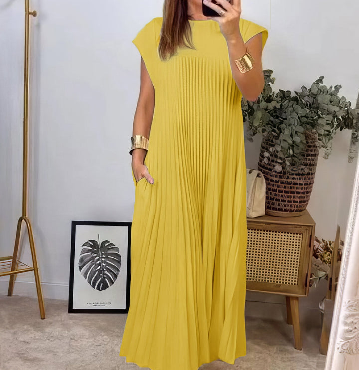 Sleeveless pleated dress, front view worn by model, hand in pocket, holding phone, gold cuffs