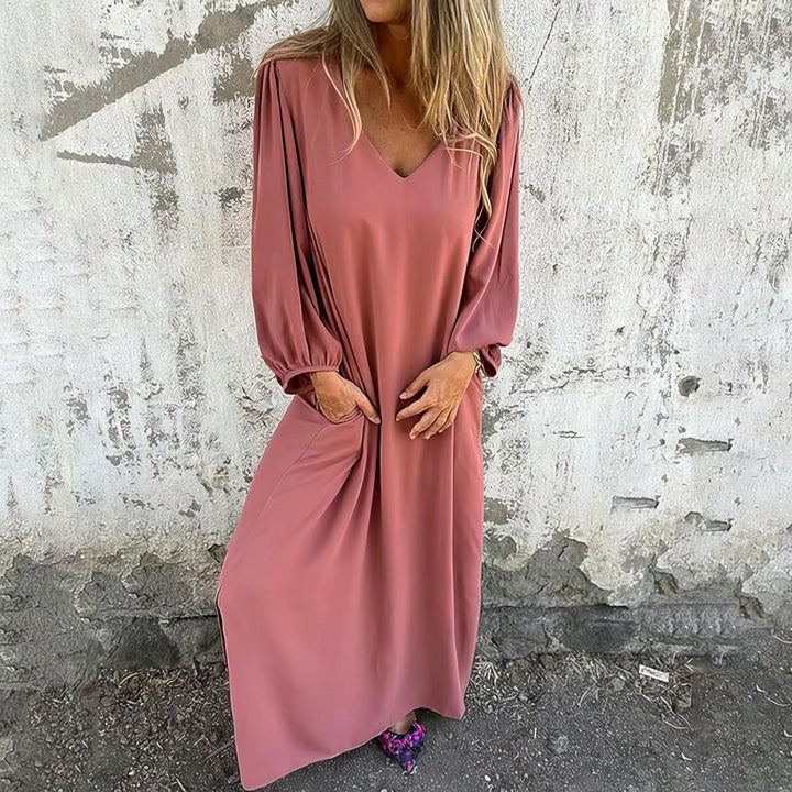 Front view of a woman wearing a pink bohemian maxi dress with pockets, both hands in pockets