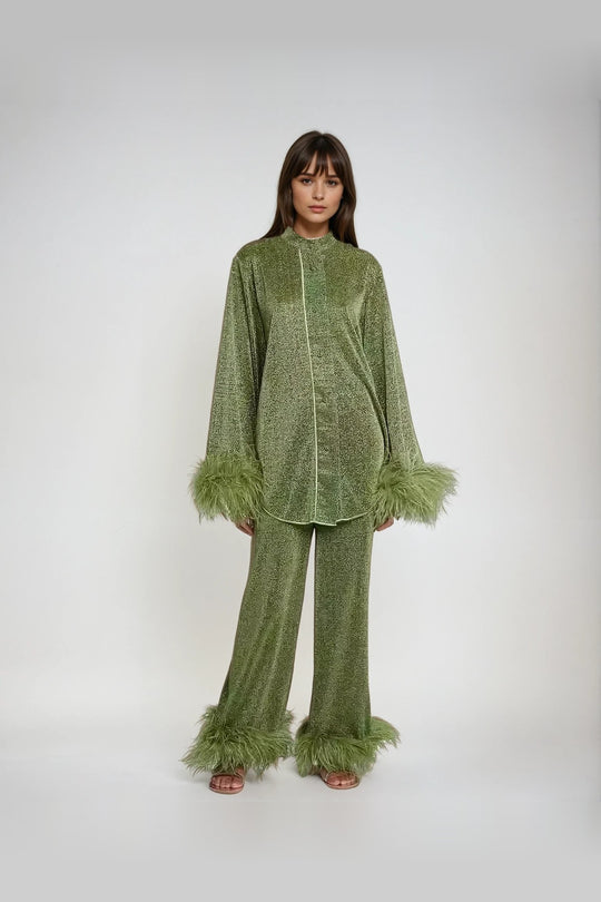 Front view, model wearing a sparkling green two-piece set with feather cuffs and feather hems