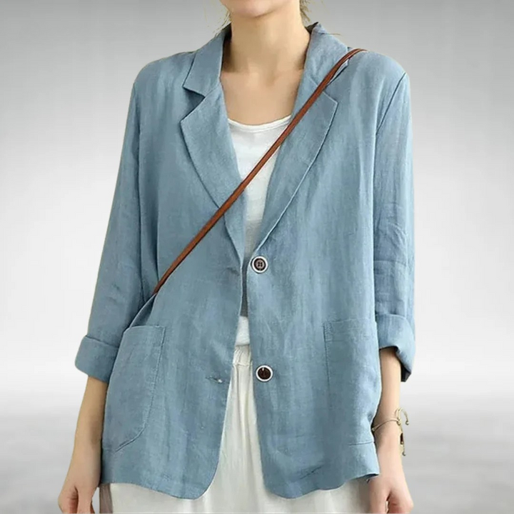Front view of a model wearing a light blue casual chic blazer with two buttons and rolled up sleeves