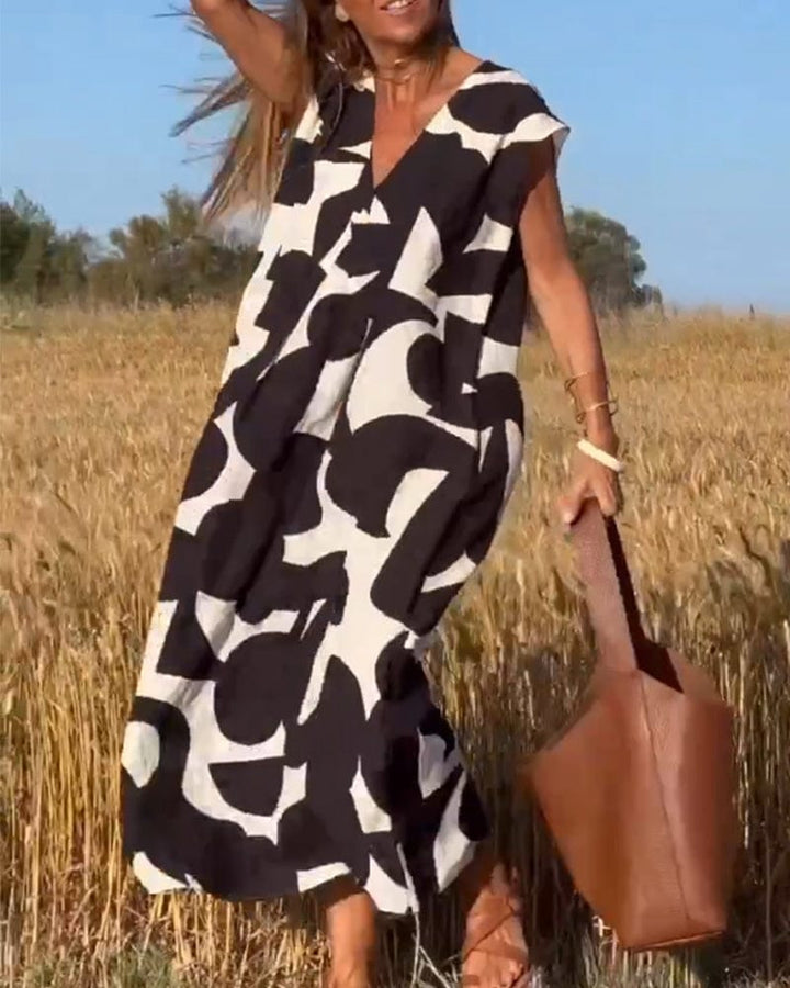 Front view of a model wearing a black and white abstract print vintage long dress in a field