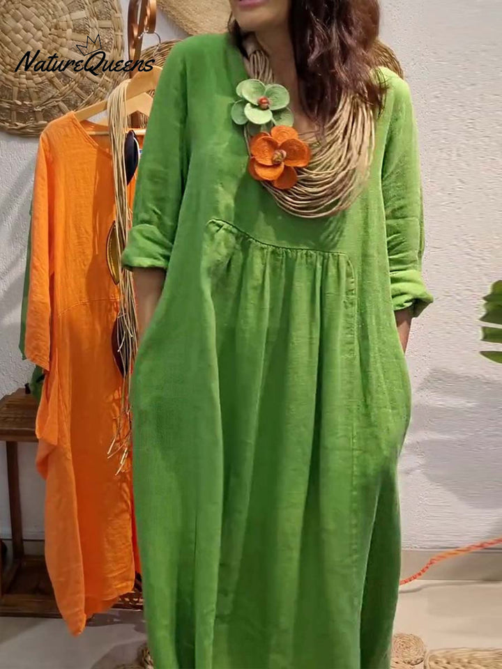 Front view, model wearing a green V-neck cotton linen dress with 3/4 sleeves and large pockets