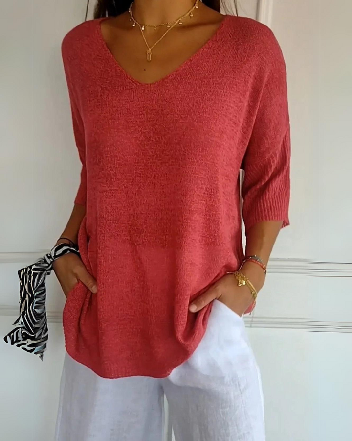 Front view of a model wearing a coral pink breathable cotton top with a V neckline and white linen pants