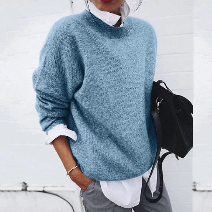 Front view of a model wearing a light blue oversized knit jumper over a white shirt with grey pants