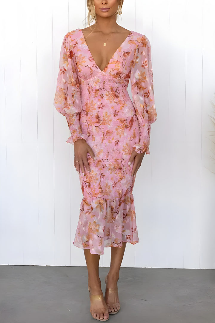 Front view, elegant dress worn by model, pink with orange floral print, deep V neckline, puff sleeves, midi length