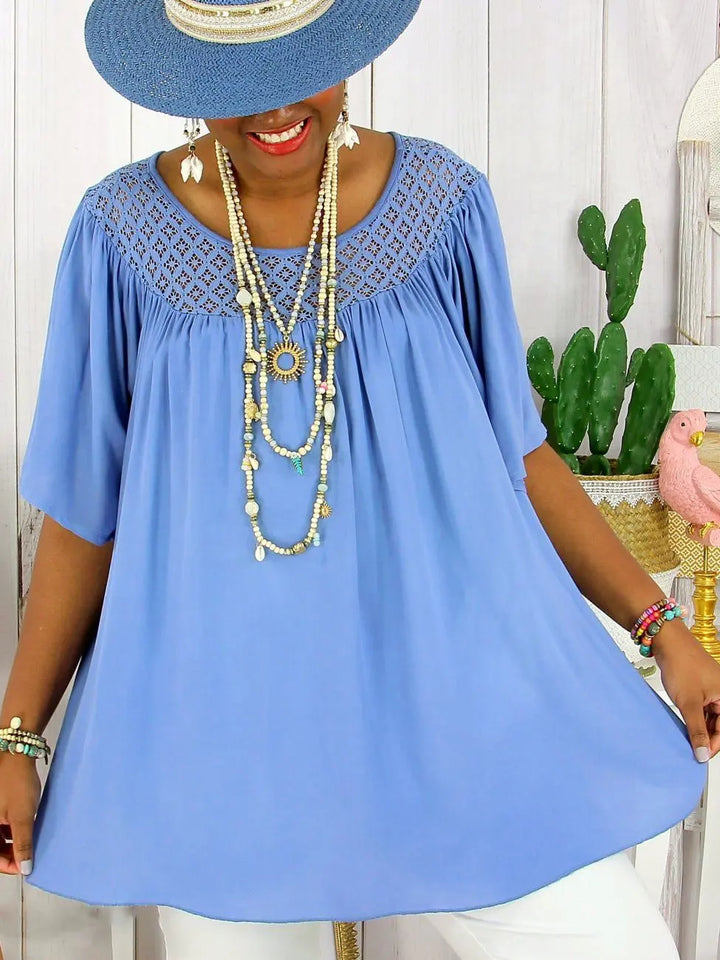 Front view, model wearing a blue loose fit summer lace top with a wide brim hat and necklaces
