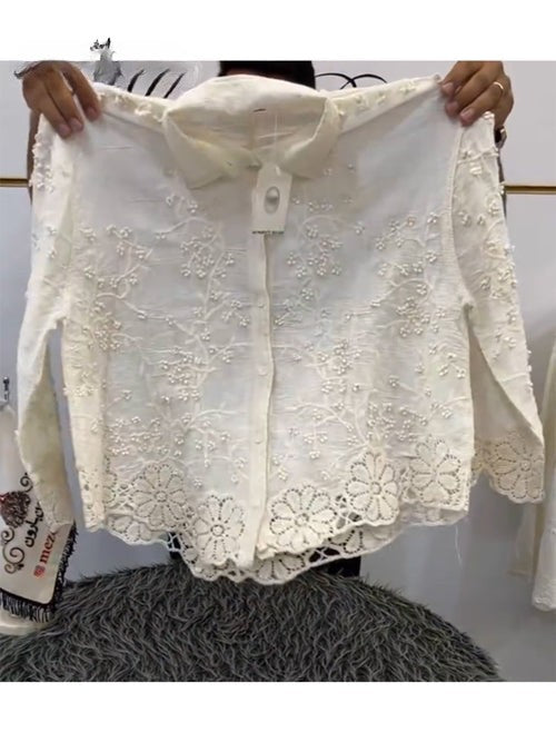 Front view of a white cotton casual shirt with 3D flower embroidery and a scalloped hem held up by hands
