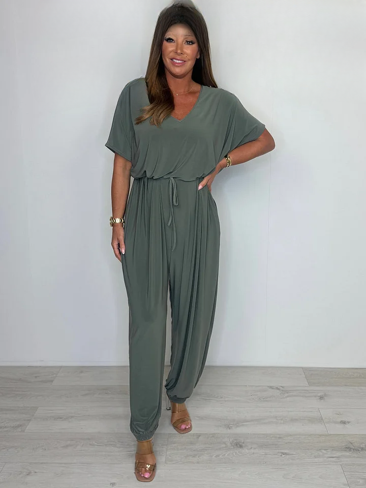 Front view of a model wearing a khaki V-neck jumpsuit with a tie waist and wide legs